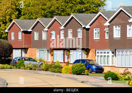 Reihe von Häusern in Wohnstraße von Immobilien-Gehäuse Grundstücksentwicklung identische Einfamilienhäuser individuelle Gärten & Auto Auffahrt England GB Stockfoto