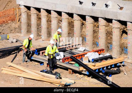 Arbeiter Harthüte & Jacken mit hoher Sichtbarkeit ausgesetzt Betonpfähle & Pfahlkappe auf einem Teil einer Stützmauer Struktur für eine Autobahnbrücke England Großbritannien Stockfoto