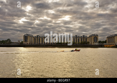 Ein kleines Motorboot Segeln vorbei an Gebäuden am Ufer der Themse in London.  Foto von Gordon Scammell Stockfoto