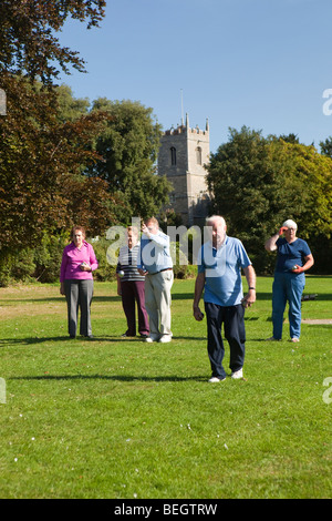 England, Cambridgeshire, Huntingdon, Hartford, Rentner spielen Boule am Flussufer grün unter Kirchturm Stockfoto