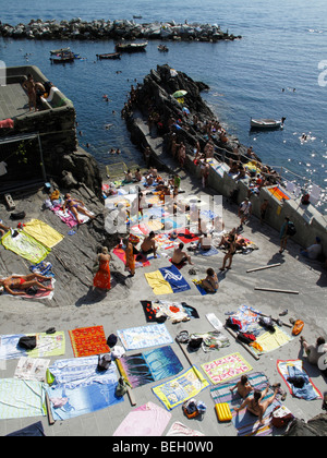 Handtücher von Sonnenanbeter auf dem Slipway am Manarola in der Region Cinque Terre an der italienischen Riviera oder Riviera di Levanto angelegt Stockfoto