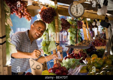 Porträt eines Obst-Verkäufer Spritzwasser über Früchte an einem Marktstand, Santo Domingo, Dominikanische Republik Stockfoto