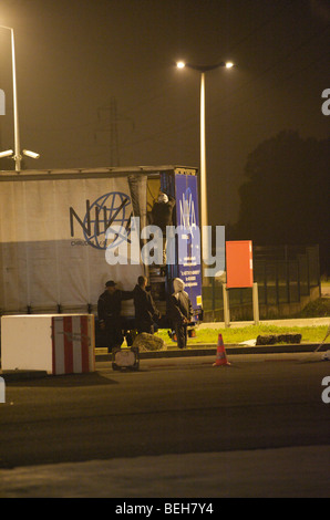 Calais, Flüchtlinge, die nach Großbritannien zu gelangen hofft Klettern LKW auf Parkplätzen auf nightime Stockfoto