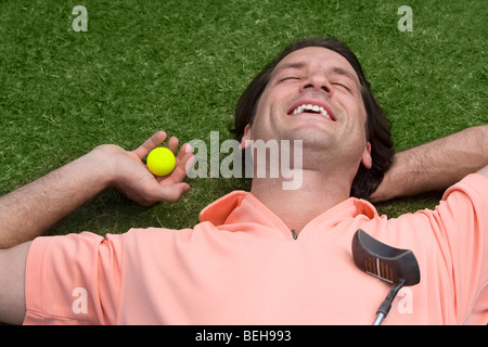 Nahaufnahme eines Mitte erwachsenen Mannes liegen auf einem Golfplatz und halten einen Golfball Stockfoto