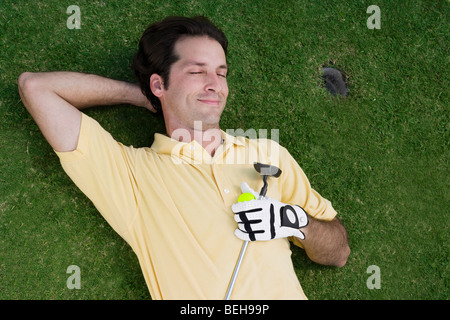 Erhöhte Ansicht eines Mitte erwachsenen Mannes liegen auf einem Golfplatz mit einem Golfball und einem Golfclub Stockfoto