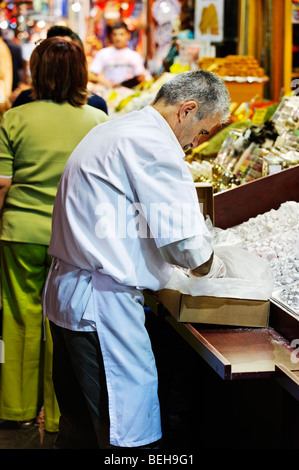 Ein Ladenbesitzer füllt seine Anzeige von Lokum (türkische Freude) vor seinem Geschäft im großen Basar von Istanbul. Stockfoto