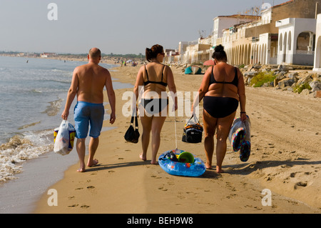 Ein Mann und zwei übergewichtige Frauen am Strand entlang In Badebekleidung Stockfoto