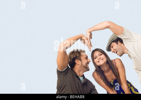 Niedrigen Winkel Ansicht von Mitte erwachsenen Mann und ein junger Mann macht eine Herzform vor einer jungen Frau Stockfoto