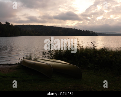 Zwei Kanus auf eine Ufer des Sees von zwei Flüssen im Morgengrauen ruhig fallen Landschaft. Algonquin Provincial Park, Ontario, Kanada. Stockfoto