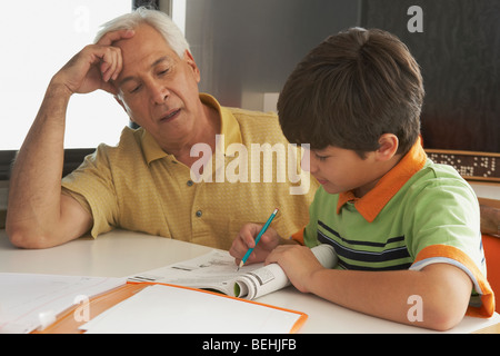 Senior woman sein Enkel in seine Hausaufgaben zu helfen Stockfoto