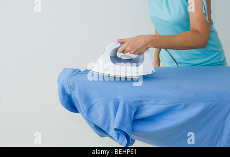 Mitte Schnittansicht einer Frau auf ein Polo-Shirt Bügeln Stockfoto