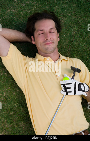 Erhöhte Ansicht eines Mitte erwachsenen Mannes liegen auf einem Golfplatz mit einem Golfball und einem Golfclub Stockfoto