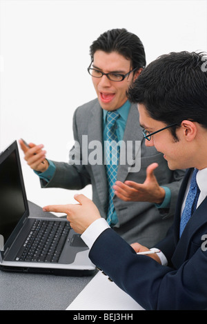 Zwei Geschäftsleute, die vor einem Laptop in einem Meeting sitzen Stockfoto