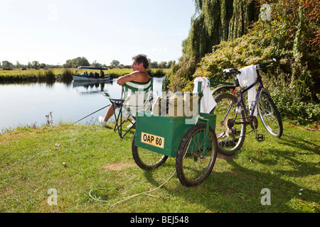 England, Cambridgeshire, Huntingdon, Hartford, Rentner mit Anhänger am Fahrrad Angeln im Fluss Great Ouse Stockfoto