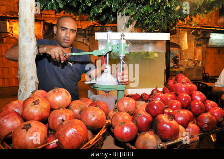 Israel, Acre, Mann presst frischen Granatapfel-Saft an einem Stand auf dem Markt Stockfoto