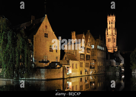 Glockenturm und mittelalterliche Häuser beleuchtet in der Nacht am Kanal in der Stadt Brügge, West-Flandern, Belgien Stockfoto