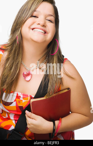 Porträt einer jungen Frau hält ein Tagebuch und lächelnd Stockfoto