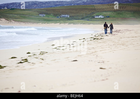 Ein junges Paar gehen hand in hand an einem einsamen Sandstrand, Isle of Harris, Schottland Stockfoto