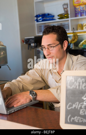 Männliche Verkäuferin mit einem Laptop in einem Coffee-shop Stockfoto