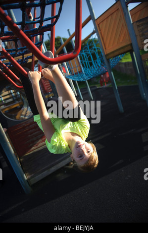 10 Jahre alte pre-teen junge Mädchen spielen auf Klettern Frame Spielgeräte auf einem öffentlichen Spielplatz, UK Stockfoto