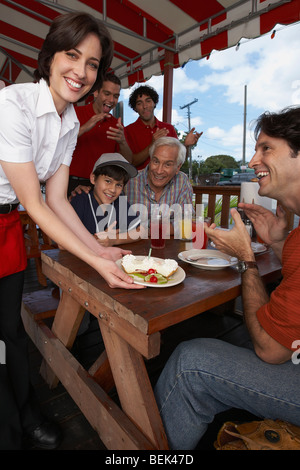 Porträt einer jungen Frau Dessert zu einem Mitte erwachsenen Mann feiert den Geburtstag seines Sohnes in einem Restaurant serviert Stockfoto