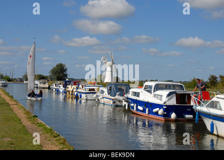 Cruiser mit Segeln Yacht verlassen und Thurne Mill jenseits im Thurne Dyke, Norfolk, festgemacht. Stockfoto