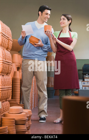 Weibliche Verkäuferin zeigt Keramik mit einem Mann Stockfoto