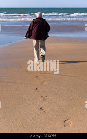 Mann zu Fuß am Strand in Richtung Meer Stockfoto