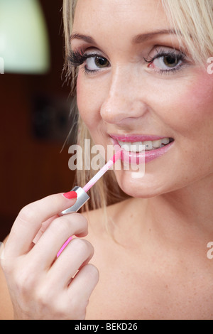 Junge blonde Frau Auftragen von Lippenstift Stockfoto