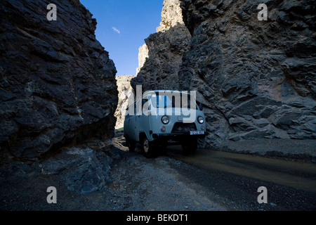 Der russische Jeep-Van aus der sowjetzeit fährt durch die enge Schlucht in der Wüste Gobi Stockfoto