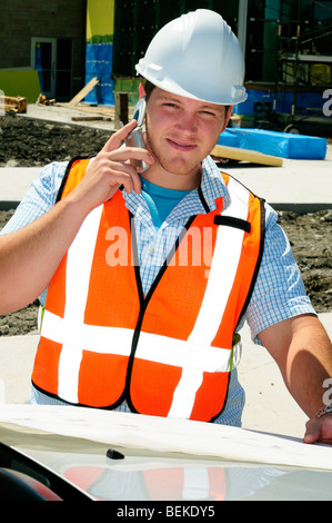 Bauingenieur mit einem mobilen Handy auf einem neuen Bauvorhaben tragen Hi Vis Weste und Helm Stockfoto