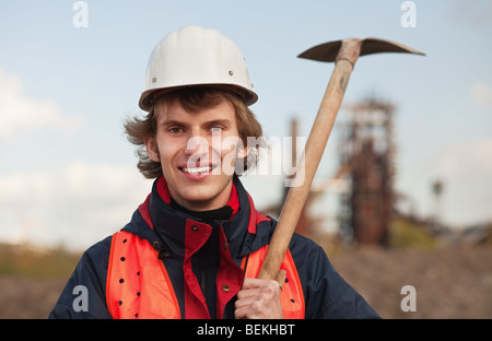 Junge Arbeiter mit Schaufel stehenden industriellen Hintergrund Stockfoto