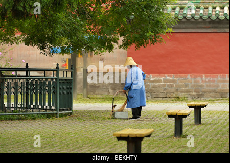 Ein Arbeiter, der aufräumte, bevor Touristen am geschäftigen Sonntagmorgen im Tiantan Park in Peking ankommen Stockfoto