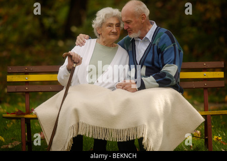 Älteres Ehepaar sitzt auf einem hölzernen Sitz Stockfoto