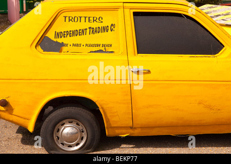 Eine gelbe Robin Reliant von nur Narren & Pferde mit Traber unabhängige Trading Co. auf der Seite im Vereinigten Königreich Stockfoto