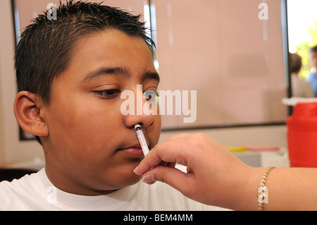 Ein 12 jähriger Junge ist für die 2009 H1N1 Influenza, auch bekannt als die Schweinegrippe, mit einem intranasalen Impfstoff geimpft. Stockfoto