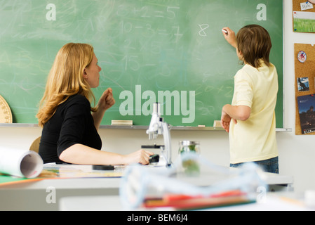 Lehrer beobachten junge an Tafel schreiben Stockfoto