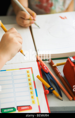 Kinder schreiben in Notizbüchern, Schulsachen in der Nähe, beschnitten Stockfoto