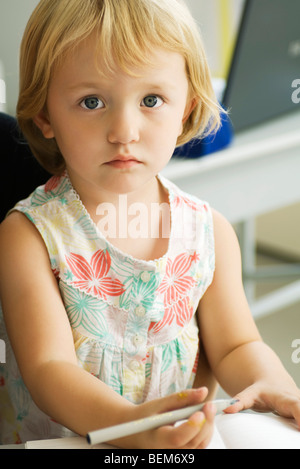 Kleines Mädchen hält Stift, Blick in die Kamera Stockfoto