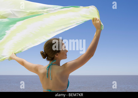 Junge Frau vor dem Meer stehen, halten Schal im Wind Stockfoto