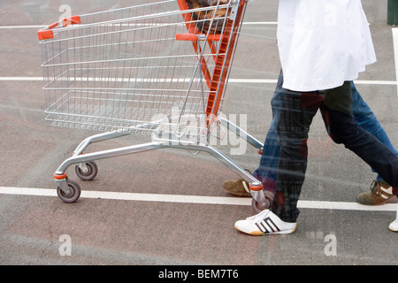 Leerer Einkaufswagen geschoben über Parkplatz Stockfoto