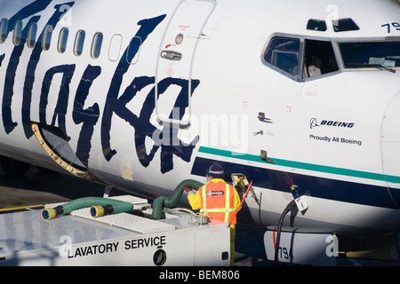 Ein Boden-Crew Arbeiter die Toilette-Service für Boeing Flugzeug von Alaska Airlines, San Francisco, Kalifornien, USA Stockfoto