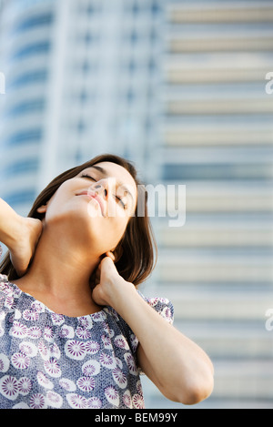 Frau massiert ihren Hals, Augen geschlossen Stockfoto