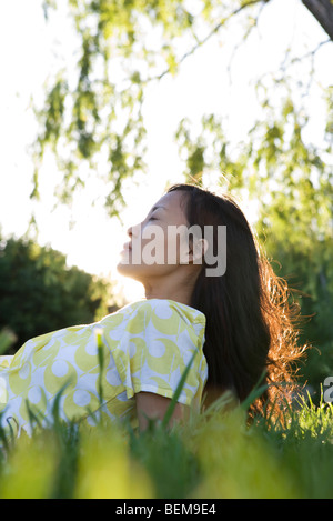 Frau, entspannend auf Rasen mit geschlossenen Augen Stockfoto