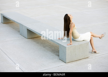 Junge Frau entspannend auf Bank im Stadtplatz, erhöhte Ansicht Stockfoto