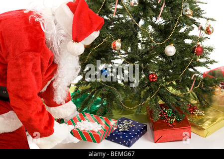 Weihnachtsmann, die Geschenke unter dem Weihnachtsbaum zu setzen. Weißen Hintergrund. Stockfoto