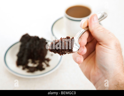 Nahaufnahme von einem Stück Schokoladenkuchen auf eine Gabel in die Hand eines Mannes. Geringe Schärfentiefe Stockfoto