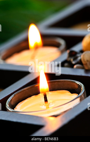 Brennende Kerzen in Glashaltern und Holz stehen Stockfoto