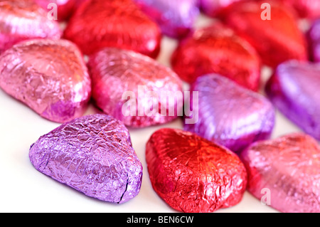 Valentinstag Pralinen verpackt in rot und lila Folie auf weißem Hintergrund Stockfoto