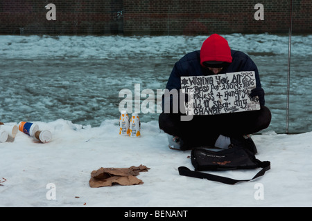 Obdachloser Mann sitzt im Schneidersitz auf Schnee in der Nähe der Millennium Bridge in London, Februar 2009 Stockfoto